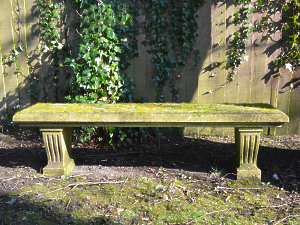 A weathered carved natural limestone garden bench