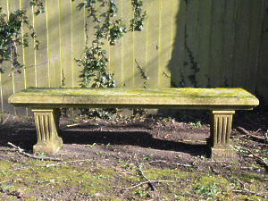 A weathered carved natural limestone garden bench