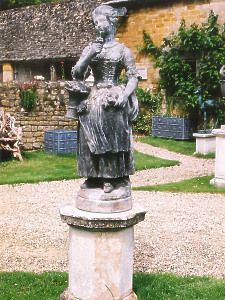 A charming statue depicting a maiden in 18th century dress carrying a basket of flowers