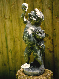 A charming 19th Century lead statue depicting a cherub holding aloft a sphere