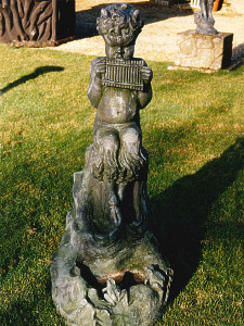 A charming lead statue of Pan seated upon a stylised rocky base incorporating a small pool