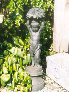 A 19th Century cast iron figure of a boy holding aloft a basket of grapes with vines