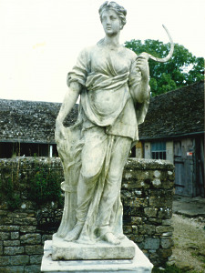 A 19th Century weathered composition stone statue depicting Ceres, the Goddess of Agriculture.  One of a pair of Flora.