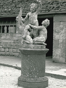 A charming trio of 19th Century composition stone Putti raised on a circular stone pedestal