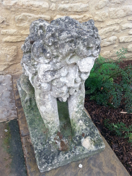 A pair of characterful seated stylised Bath stone dogs 