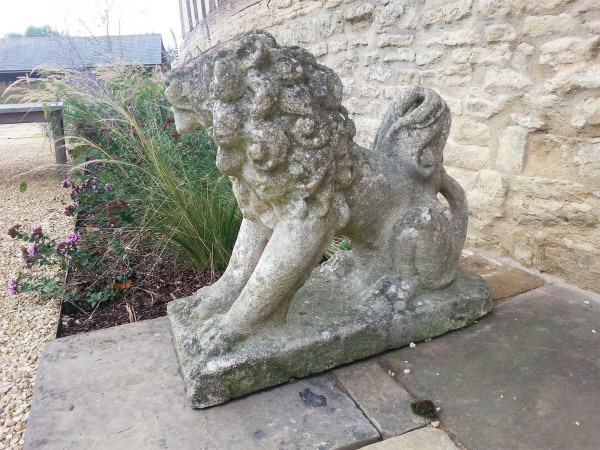A pair of characterful seated stylised Bath stone dogs 