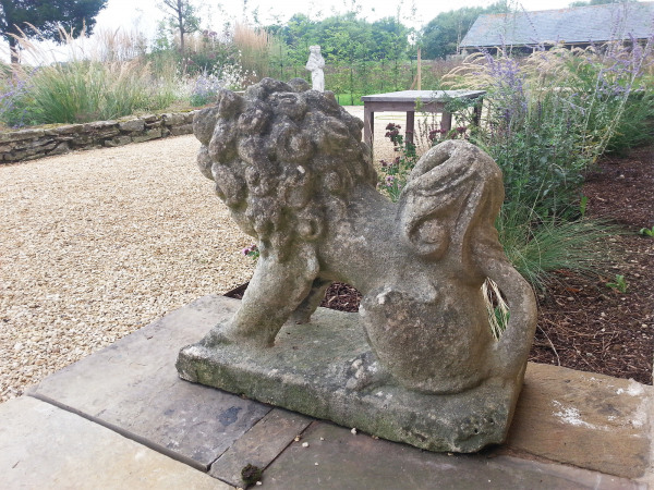 A pair of characterful seated stylised Bath stone dogs 