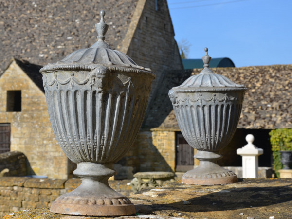 A pair of lead finial urns in the Adams style