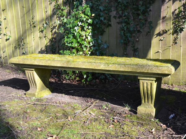 A weathered carved natural limestone garden bench