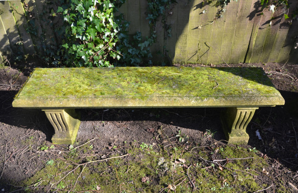 A weathered carved natural limestone garden bench