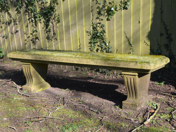 A weathered carved natural limestone garden bench