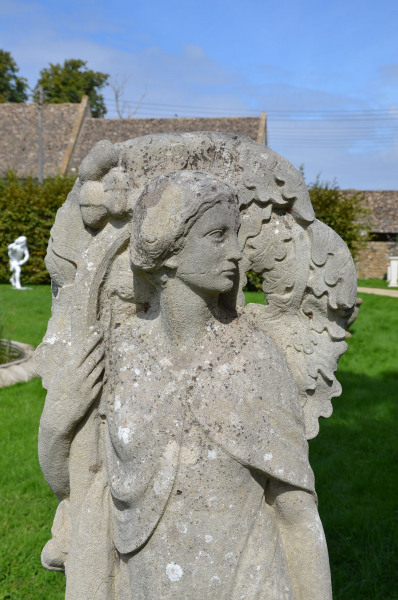 A carved stone niche figure in the Arts and Crafts style depicting an allegory of Autumn