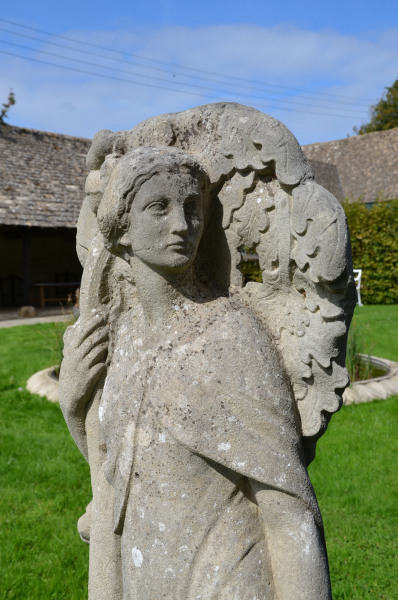 A carved stone niche figure in the Arts and Crafts style depicting an allegory of Autumn