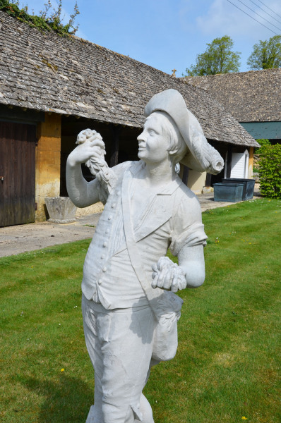 A French carved Caen stone figure of a grape picker