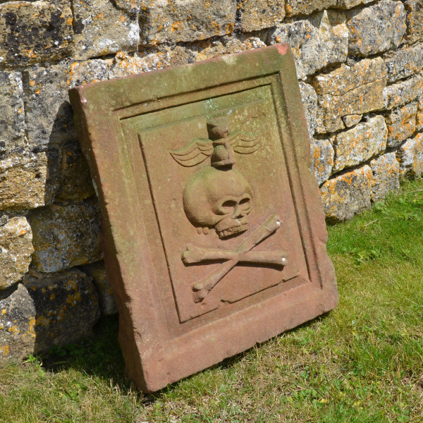 An 18th century sandstone plaque showing a skull and crossbones