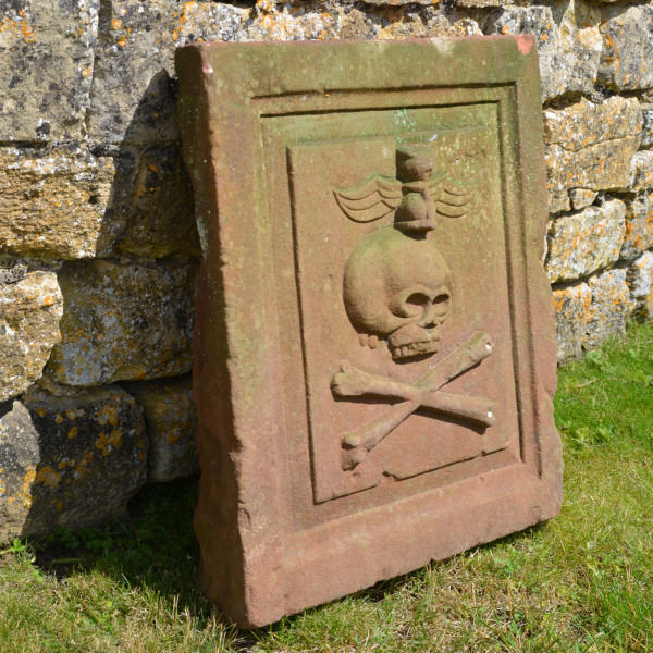 An 18th century sandstone plaque showing a skull and crossbones