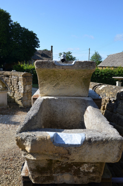 A three tier stone fountain with zinc spout in the form of a stylized dolphin
